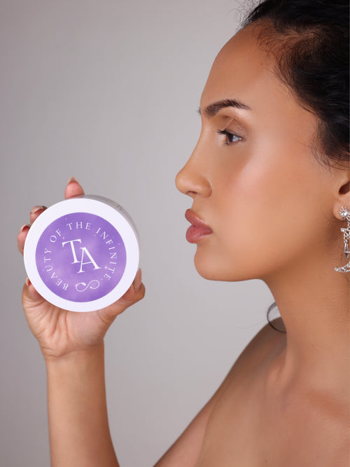 Woman holding a purple container with The Arcturian Lavender Whipped Scrub   logo against a neutral background