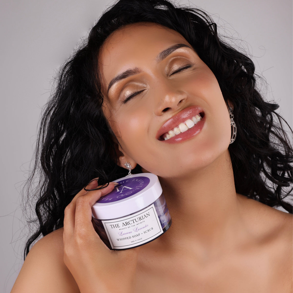 woman smiling while holding The Arcturian Lavender Whipped Scrub
