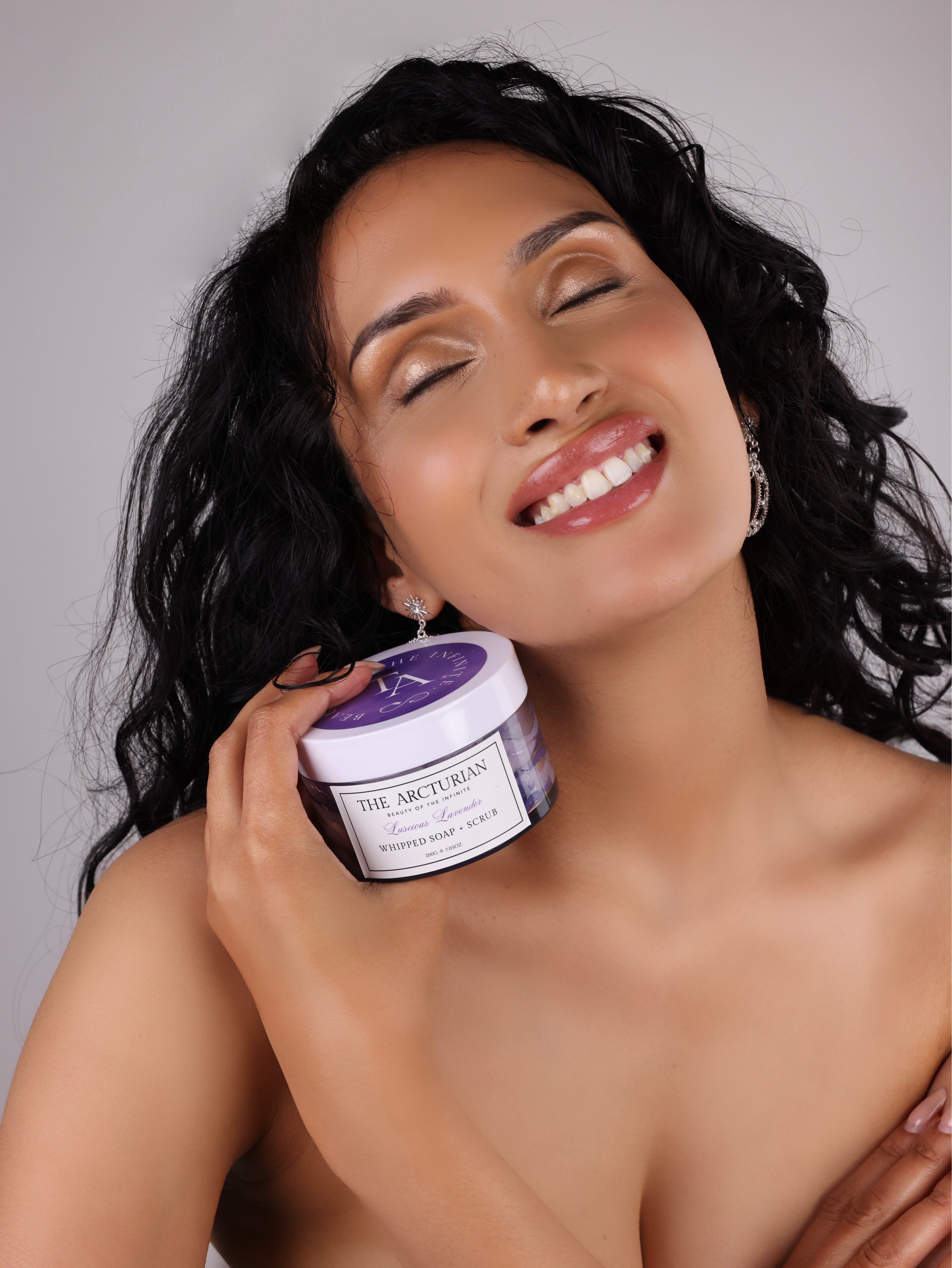 woman smiling while holding The Arcturian Lavender Whipped Scrub
